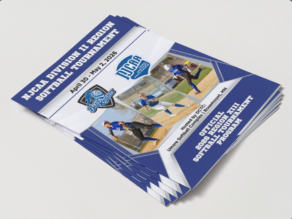 A 3D mockup of a stack of printed NJCAA Division II Region Softball Tournament programs. The cover features the DCTC Blue Knights and NJCAA logos, action photos of softball players, and blue geometric branding elements.